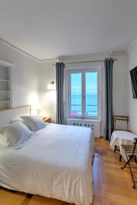 ein Schlafzimmer mit einem großen weißen Bett und einem Fenster in der Unterkunft Gîte de la Plage in Étretat