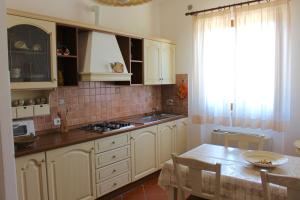 a kitchen with white cabinets and a table and a window at Agriturismo Vecchio Imposto in Massa Marittima