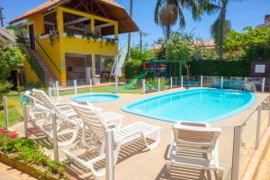 a swimming pool with chairs and a playground at Pousada Jardim Porto Belo in Porto Belo