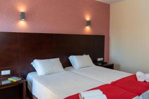 a bedroom with a large bed with white sheets and red blanket at Flag Hotel Barcelos in Barcelos