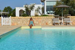 una chica sentada en el borde de una piscina en Agriturismo Residenza Gemma, en Porto Cesareo