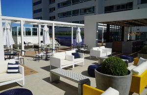 un patio con mobili bianchi, tavoli e sedie di Apart Hotel - Campos dos Goytacazes a Campos dos Goytacazes