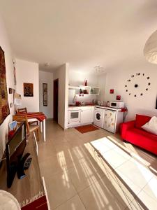 een woonkamer met een rode bank en een keuken bij La Casita Sun Beach in Caleta De Fuste