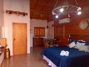 a bedroom with a blue bed and a kitchen at Aconchego da Serra Geminados in São Joaquim