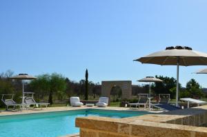 a swimming pool with chairs and umbrellas at Agriturismo Residenza Gemma in Porto Cesareo