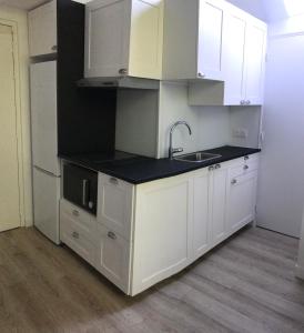 a small kitchen with white cabinets and a sink at Studio dans les écuries du chateau in Bonnelles