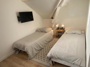 two beds in a room with a tv on the wall at Studio dans les écuries du chateau in Bonnelles