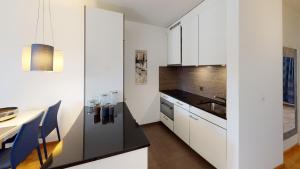a kitchen with white cabinets and a black counter top at Unique Serviced Living @ Airport Line Colmarer in Basel