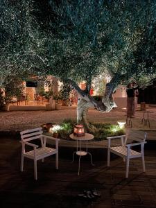 une table et deux chaises sous un arbre la nuit dans l'établissement Masseria Trulli&Stelle B&B, à Noci