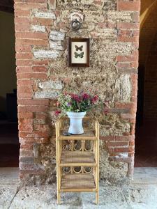 un jarrón de flores en una mesa junto a una pared de ladrillo en Podere La Chiusella B&B, en Rapolano Terme