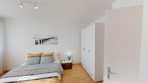 1 dormitorio con cama y pared blanca en Unique Serviced Living @ St. Johann Davidsrain en Basilea