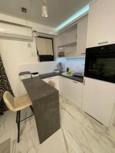 a kitchen with white cabinets and a black microwave at Liga apartment in Vračar (historical)