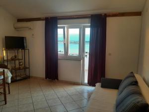 a living room with a large window with a view of the ocean at Apartments Donadic I, Caska in Novalja