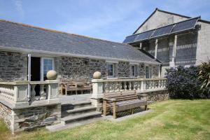 un edificio de piedra con porche y banco en Chy un Lur Rural cottage en Truro