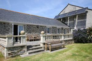 a stone building with a porch and a bench at Chy un Lur Rural cottage in Truro