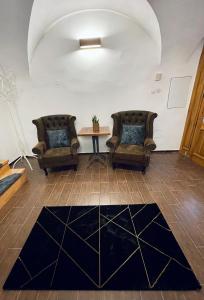 dwa krzesła i stół w pokoju z dywanem w obiekcie Dorfel w Koszycach