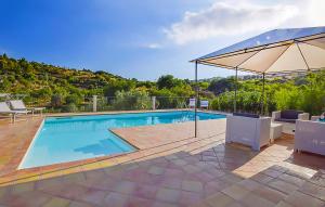 a swimming pool with an umbrella and chairs and a table at Ceretanum Holiday House in Giarratana