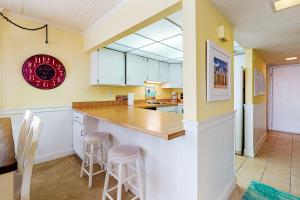 a kitchen with white cabinets and a counter with stools at Ocean Hideaway 511 in Ocean City