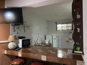 a kitchen with a table with a microwave and a television at Apartamentos Aconchegantes, Villa da Praia in Praia do Forte