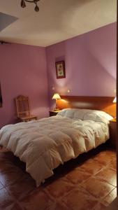 1 dormitorio con cama grande y pared morada en El encinar de las Hoces - Vivienda de uso turístico en Castrillo de Sepúlveda