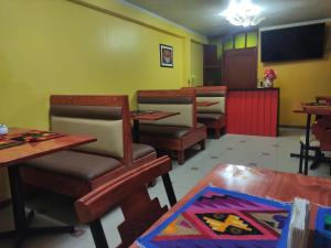 una sala da pranzo con tavoli, sedie e TV di Casa Sucre Ayacucho ad Ayacucho