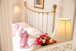 a bed with pink pillows and a bouquet of flowers at Higher Weddicott Barn Holiday Cottage - Self Catering in Chagford