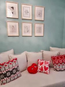a white couch with pillows and pictures on a wall at Apartamenti Romantika in Jūrmala