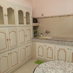 a kitchen with white cabinets and a sink at Maison de vacances zuine in Oujda
