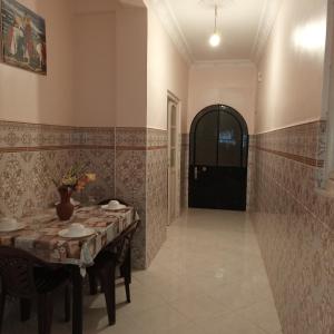 a dining room with a table and a black door at Maison de vacances zuine in Oujda