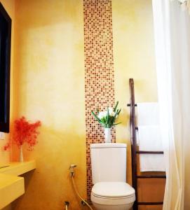 a bathroom with a toilet and a tile wall at Benyada Lodge - Surin Beach in Surin Beach