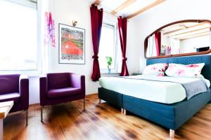 um quarto com uma cama e 2 cadeiras roxas em A-Apartment em Bad Säckingen
