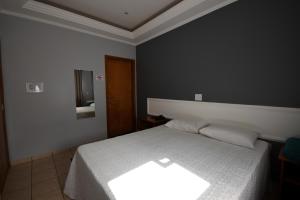 a bedroom with a white bed and a mirror at HOTEL ABAPORU in Adamantina