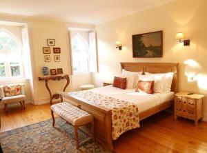 a bedroom with a bed and a chair and two windows at Casa Holstein Quinta de Sao Sebastiao Sintra in Sintra