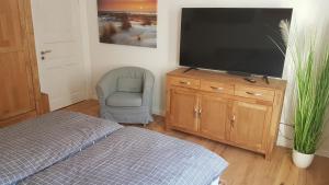 sypialnia z telewizorem z płaskim ekranem i krzesłem w obiekcie Nordic Oak Line w Kilonii