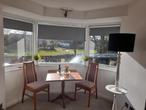 a dining room with a table and chairs and two windows at The Studio in Windermere