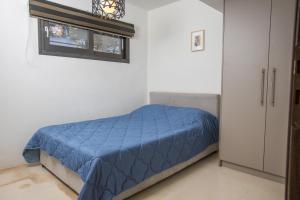 a bedroom with a bed with a blue comforter and a window at Raise Spetses Sea View Villa in Spetses