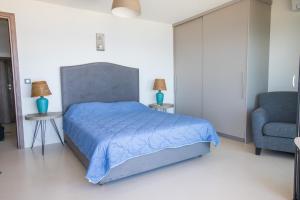 a bedroom with a blue bed and a chair at Raise Spetses Sea View Villa in Spetses