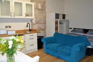 a living room with a blue couch and a bed at Hebble end works apartment 3 in Hebden Bridge