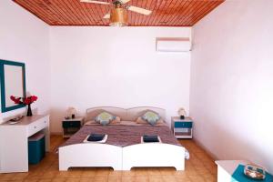 a bedroom with a large white bed with a ceiling at Villa Elpida in Agios Georgios