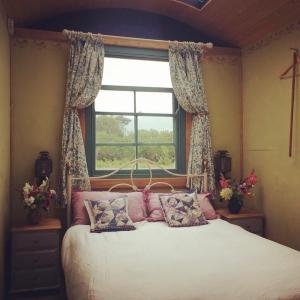 um quarto com uma cama grande e uma janela em Sky View Shepherd's Huts with Woodburning Hot Tub em Redruth