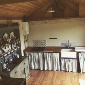 uma cozinha com uma mesa e um lavatório num quarto em Sky View Shepherd's Huts with Woodburning Hot Tub em Redruth