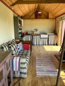 a living room with a couch and a kitchen at Sky View Shepherd's Huts with Woodburning Hot Tub in Redruth