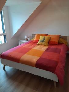 a bed with a colorful comforter in a room at Maison TY PRAD bord de mer in Sarzeau
