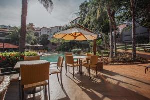 uma mesa e cadeiras com um guarda-sol ao lado de uma piscina em Rio Quente Resorts - Hotel Luupi em Rio Quente
