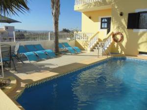a swimming pool with chairs and a house at Apartamentos Paradise Fuseta in Fuzeta