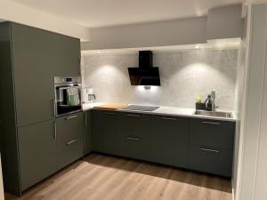 een keuken met zwarte kasten en een wastafel bij Lofoten - New apartment, close to airport. in Leknes
