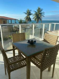 een tafel en stoelen op een balkon met uitzicht op de oceaan bij Flat pé na areia do Caribessa in João Pessoa