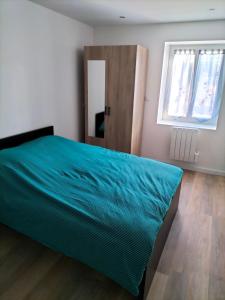 Schlafzimmer mit einem Bett mit blauer Bettdecke und einem Fenster in der Unterkunft Appartement 2 pièces in Rive-de-Gier