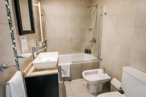 a bathroom with a sink and a toilet and a tub at Departamentos La Vela in Ushuaia +47 photos