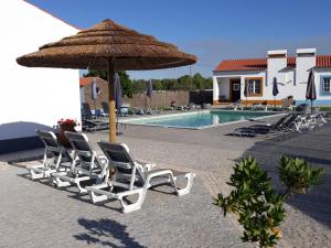 a group of chairs and an umbrella next to a pool at Casas da Minh'Alma in Reguengos de Monsaraz